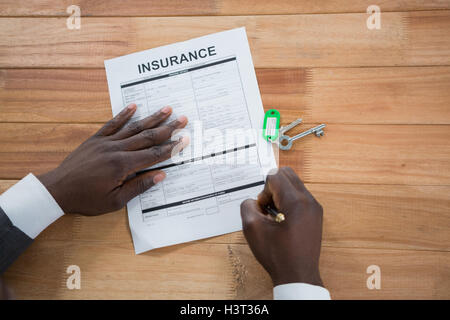 Les mains d'un homme signature le document d'assurance Banque D'Images