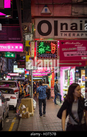 Les gens la marche à un trottoir à l'Hennessy Road à Causeway Bay, Hong Kong la nuit. Banque D'Images