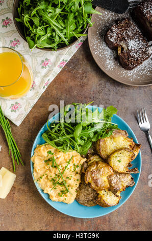 Croustillant de pommes de terre écrasées, des œufs brouillés et peu de jus, salade et gâteau pour le petit déjeuner délicieux Banque D'Images