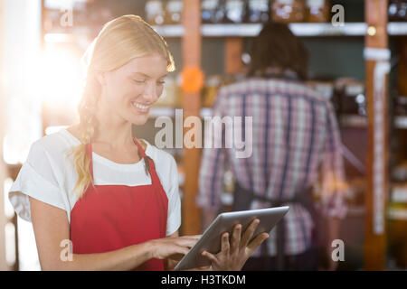 Le personnel féminin using digital tablet in supermarket Banque D'Images