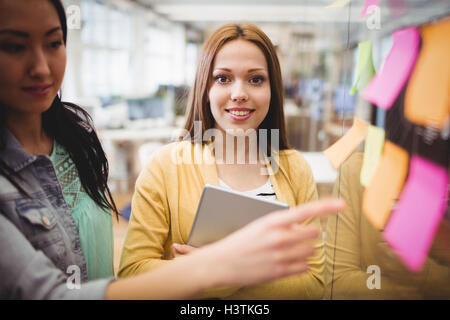 Editeur de photos debout près de leurs collègues de sexe féminin pointant sur sticky note Banque D'Images