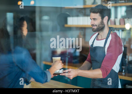 Waiter serving une tasse de café froid au client au comptoir Banque D'Images