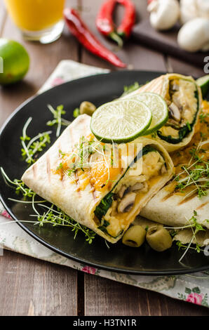 Petit-déjeuner burrito avec œufs, cheddar, microgreens, olives et champignons grillés Banque D'Images