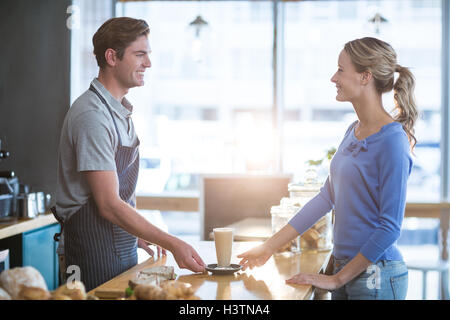 Waiter serving une tasse de café froid au client au comptoir Banque D'Images