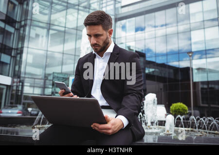 Businessman using mobile phone and laptop Banque D'Images