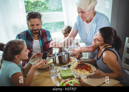 Femme âgée servant repas pour sa famille Banque D'Images