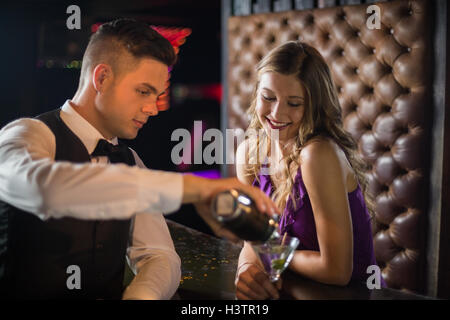 Waiter pouring cocktail dans un verre au comptoir du bar femme Banque D'Images