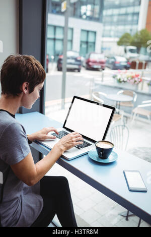 Businesswoman having une tasse de café tout en utilisant un ordinateur portable Banque D'Images