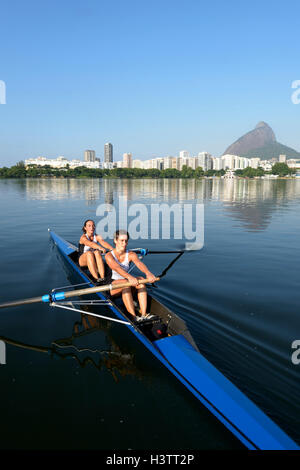 Deux jeunes femmes qui participent à la formation de l'aviron tôt le matin dans la Lagoa Rodrigo de Freitas Lagoon, à Rio de Janeiro Banque D'Images