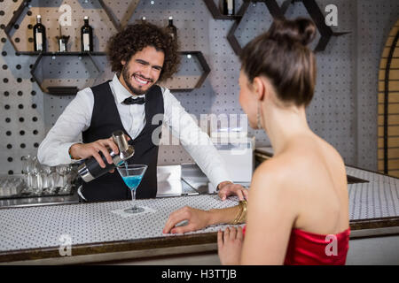 Waiter pouring cocktail au comptoir de bar en verre de womans Banque D'Images