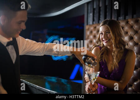 Waiter pouring cocktail dans un verre au comptoir du bar femme Banque D'Images
