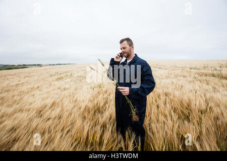 L'examen de cultures, tout agriculteur talking on mobile phone dans le domaine Banque D'Images