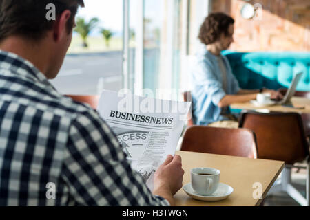 La lecture d'un journal d'affaires de l'homme in coffee shop Banque D'Images