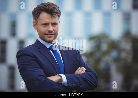 Handsome businessman standing with arms crossed Banque D'Images