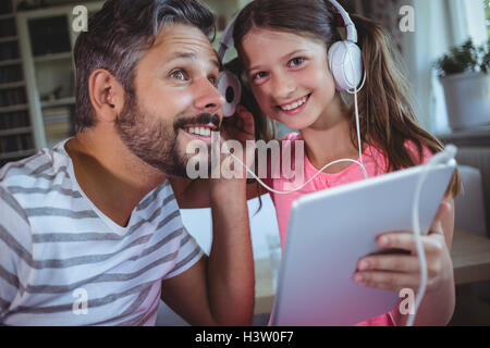 Père et fille à l'écoute de la musique sur tablette numérique Banque D'Images