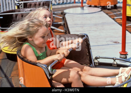 Années 1980 DEUX BLONDES SOEURS ÉQUITATION HURLANT DE AMUSEMENT PARK RIDE LE FOUET HOLDING LE SERRÉ Banque D'Images