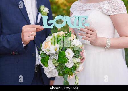 Bride and Groom holding mot amour en bois Banque D'Images