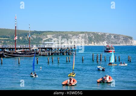 Le Moonfleet tallship amarrée le long de la jetée victorienne avec des canots et un ferry dans la baie, Swanage, Dorset, Angleterre, Royaume-Uni. Banque D'Images