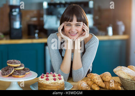 Portrait of young assis au comptoir avec sweet food on table