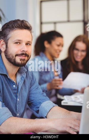 Confident businessman using laptop contre les collaborateurs Banque D'Images