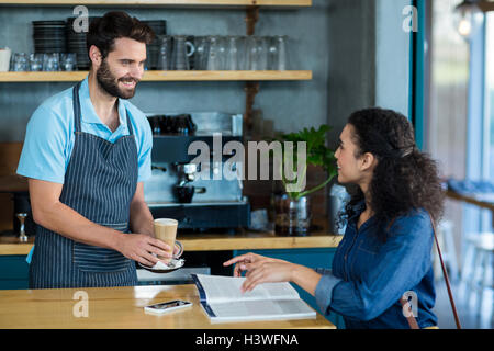 Waiter serving une tasse de café froid au client à table Banque D'Images