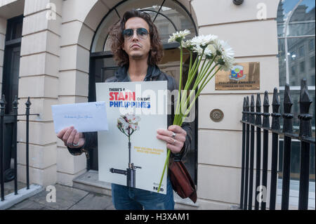 Londres, Royaume-Uni. 13 Oct, 2016. Un homme détient les fleurs blanches, une affiche et une lettre qu'il y est arrivé à l'ambassade des Philippines à delvierbe pas de poursuites pour ces exécutions extra-judiciaires. Depuis son arrivée au pouvoir à la fin de juin, il y a eu plus de 3500 ces homicides illégaux dans les rues. Crédit : Peter Marshall/Alamy Live News Banque D'Images