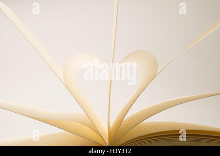 Des pages de livre blanc formant un cœur éclairé sur fond blanc Banque D'Images