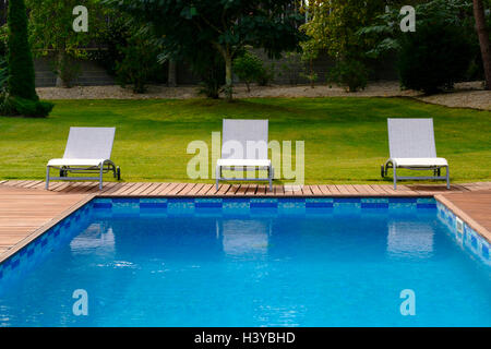 Chaises longues sur une terrasse en bois à côté d'une piscine extérieure Banque D'Images