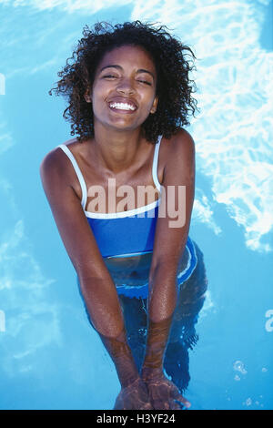 Piscine, femme, non-blancs, stand, rafraîchir l'eau, libérés du modèle, les vacances, les loisirs, l'été, l'eau, baignoire, rafraîchissements, refroidissement, nager, barboter, éclabousser, heureux, de se sentir, de bien-être, heureux, l'humeur, de façon positive, très proche Banque D'Images