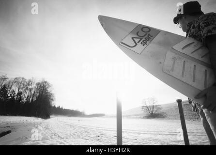 Paysage d'hiver, l'homme, New jersey shirt, surfboard, contrejour, b/w, hiver, paysage, neige, froid, s'échapper, les vacanciers, des lunettes solaires, chapeau, résister, prêt pour d'une maison de vacances, appartement de vacances, envie de voir le rêve, rêve, désir, locations, indépendance, liberté, désir, rêve Banque D'Images