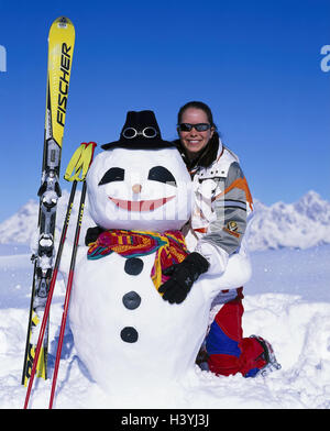 Paysage de montagne, femme, bonhomme de neige, construire, heureux, montagnes, des vêtements d'hiver, vacances d'hiver, vacances, loisirs, activité, plaisir, plaisir, de la joie, de l'humeur, de façon positive, hiver, neige, skis, bâtons de ski Banque D'Images