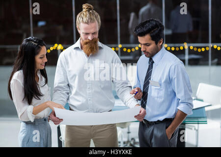 Businesswoman et businessmen discussing over blueprint Banque D'Images