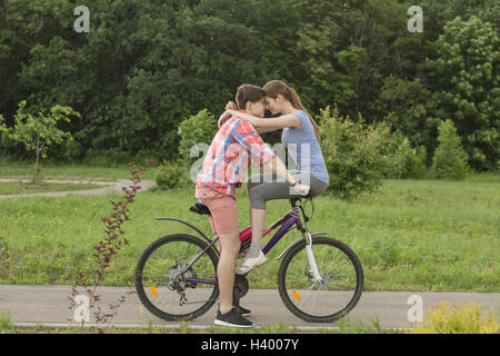 Couple assis face à face sur location contre des arbres au parc Banque D'Images