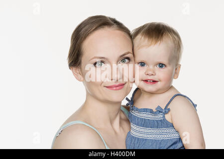 Portrait of smiling mother carrying cute girl against white background Banque D'Images