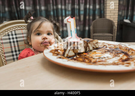 Portrait of cute girl sticking out tongue avec messy visage tout en ayant cake Banque D'Images