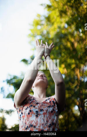 Low angle view of woman exercising Tai Chi contre des arbres Banque D'Images