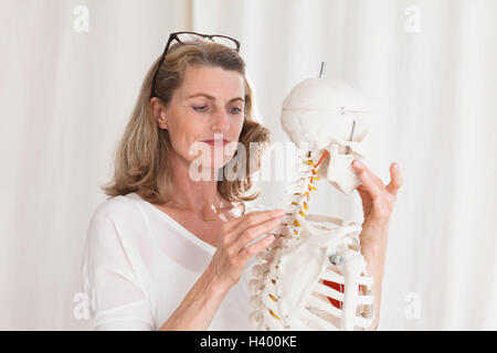 Confident female doctor looking at squelette debout en clinique Banque D'Images