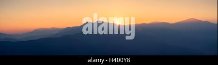 Vue panoramique sur les collines et montagnes avec brume bleue à l'heure d'or et magnifique coucher de soleil Banque D'Images