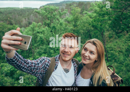 Smiling couple prenant en selfies smart phone at forest Banque D'Images