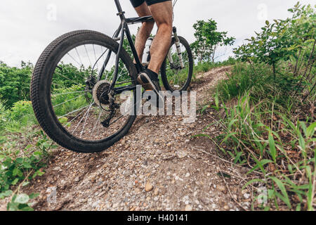 La section basse de l'homme équitation vtt sur un chemin de terre Banque D'Images