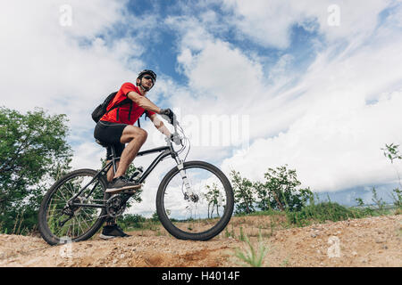 Low angle view of man riding mountain bike en milieu rural contre le ciel Banque D'Images