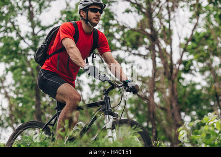 Homme confiant équitation vtt en forêt Banque D'Images