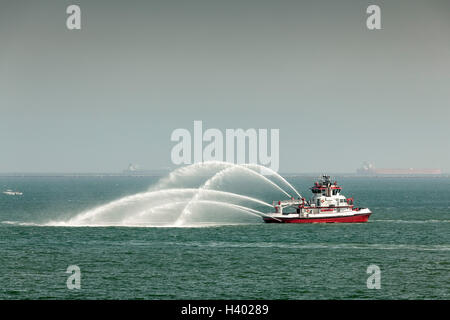 Bateau feu pulvériser de l'eau dans la mer contre le ciel Banque D'Images