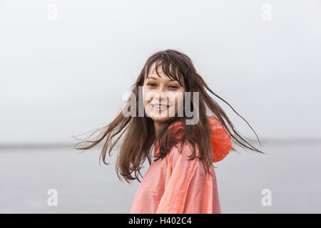 Portrait of smiling woman wearing raincoat debout contre un ciel clair Banque D'Images