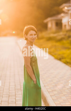 Side view of woman wearing dress debout sur un trottoir au cours de journée ensoleillée Banque D'Images