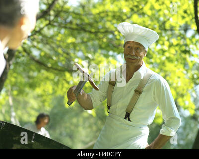 Jardin, cuisine, Pac, grill, liers, le geste, l'homme de la saucisse, des personnes âgées, des femmes, des amis, ensemble, fun, grill, saucisses, Würstel, Grillewürstel, préparation, hobby, cuisinier, cap, coiffures, tablier, les loisirs, l'été, à l'extérieur, ensoleillé Banque D'Images