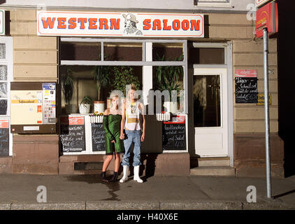 Localement, fenêtre, couple, tenue, fashion, exceptionnellement, à l'extérieur, 'Western-Saloon', restaurant, babillards, menu, main dans la main, voir l'appareil photo, vêtements, chaussettes, réseau robe, jeans, Wellington, aslant, l'extravagance, style, style, look, style, contraste, Banque D'Images