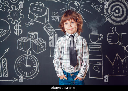 Petit garçon comme businessman ou enseignant de porter chemise et cravate sur un fond sombre avec business school photo Banque D'Images