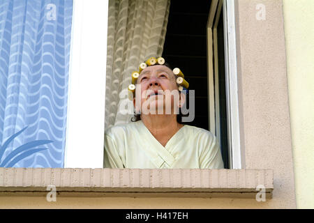 Maison d'habitation, senior, cheveux, bigoudis, fenêtre Vue, portrait, portrait de la femme, femme, 73 ans, de 70 à 80 ans, télévision, fenêtre, pensionné, les loisirs, l'ennui, le temps libre, la curiosité, l'observation, l'observer, regarder, d'intérêt, vieille personne, la solitude Banque D'Images