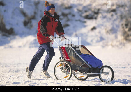 Jogger, landau, un hiver femme, l'écrou, 36 ans, baby joggers, jogging, course, du temps de loisirs, hobby, sport, l'activité, la condition physique, la joie de vie, les loisirs, la santé, de l'égaliseur de 30 à 40 ans, la neige Banque D'Images